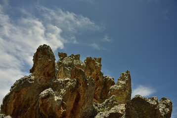 A group of rocks looking like gargoyles against dramatic clouds and a blue sky