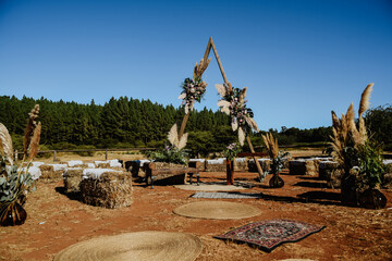 Open-air ceremony with a triangular arch and decorated with natural flowers, rural style