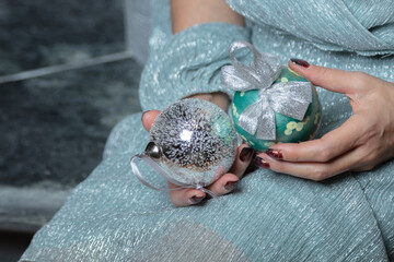 A woman holds beautiful Christmas balls in her hands. Cropped photo. Christmas concept, new year