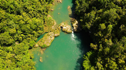 Aerial drone of Tropical Loboc river in the rainforest. Mountain river flows through green forest. Bohol, Philippines.