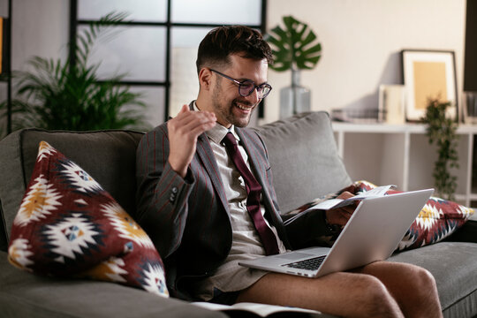 Businessman With No Pants Working At Home. Young Man Using The Laptop Having Video Call.