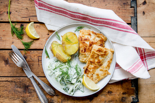 Breaded fish fillet with potatoes and cucumber salad