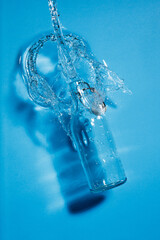 Clear Bottle of water. Blue water ripples and splashes. Water is pouring out of the bottle	