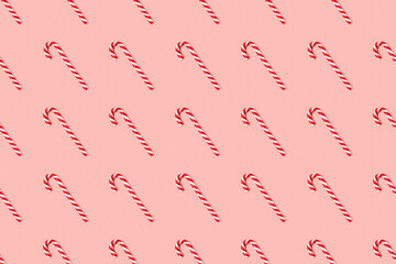 Christmas seamless pattern made of striped candy cane on a pink pastel background. Background made of food. Christmas and New year concept. Top view. Flat lay. Minimal composition
