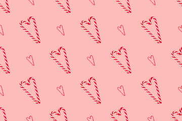 Seamless pattern made of striped candy cane laid out in the shape of heart on a pink pastel background. Background made of food. Valentine's day and Christmas concept. Top view. Minimal composition