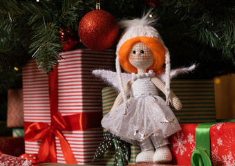 Crocheted toy doll in a white dress. Celebratory decorations.