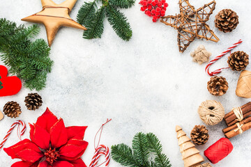 Christmas background, pine cones, wooden ornaments and decorations, fabric poinsettia flower,candy canes, fir tree branches on white table