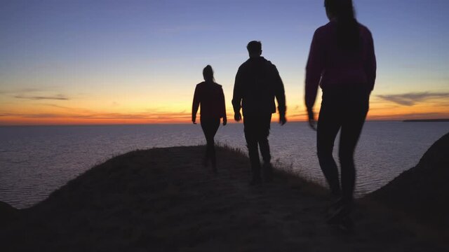 The three people walking on the mountain against the seascape