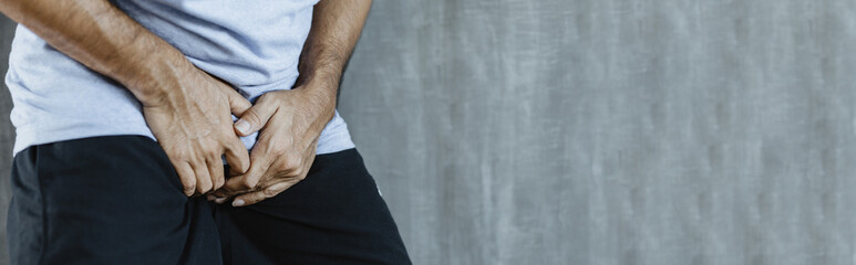 young man with hands holding his crotch for banner background with copy space