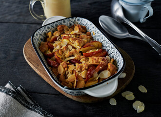 Apple crumble in a baking dish on a black wooden background