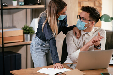 Businessman and businesswoman with medical mask in office. Colleagues working together. COVID - 19 virus protection.