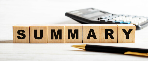 On a light background, a pen, calculator and wooden cubes with the inscription SUMMARY. Defocus