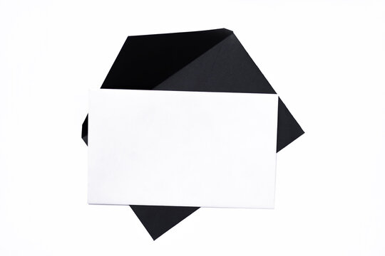 Blank white card with open black envelope. Minimalist composition on white background. Top view, empty space for text.