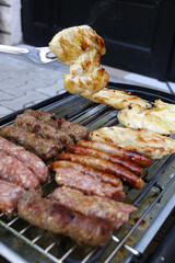 Grilling food,meat,chicken in backyard or a terrace on a small cheap electrical BBQ grill at home.Chicken meat on a bbq fork.Close up.