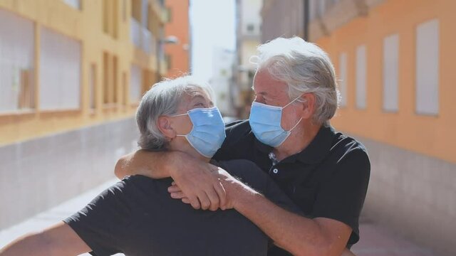 couple of two seniors wearing medical mask to prevent coronavirus (covid-19) or another type of virus - close up of faces in middle of street -  protect people satying safe together - italian people
