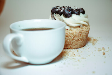 
Cupcake with cream and blueberries and a cup of coffee on a white background