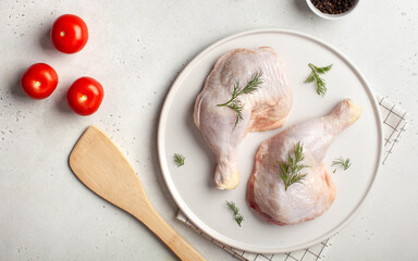 Farmed poultry. Chilled raw chicken legs on a plate with vegetables and spices. Copy space.