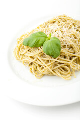 Homemade carbonara served on a white pate, topped with basil leafs and grated parmesan. Studio photo isolated on white background.