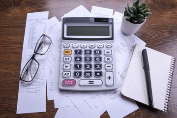 Calculator keypad with checks from the store from shopping on a wooden floor background. Top view. Copy space