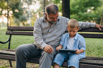 Obraz premium grandfather and grandson spending time together in public park