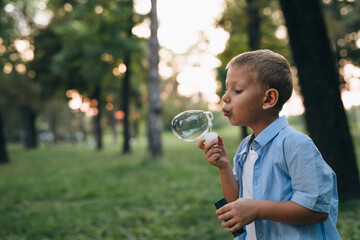 little boy playing with soap balloons in public park