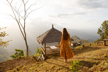 Young tourist enjoying her travel around Bali island , Indonesia. She stands in the mountains in popular viewpoint photo spot location and enjoy the view