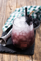 Fresh blackberry cocktail in cold glass on wooden table