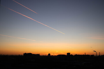 traces of a flying plane on the city's sunset sky