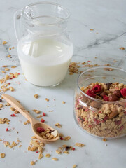 healthy and tasty granola with berries, fruits, nuts and yogurt in a glass dish with a wooden spoon on a light background