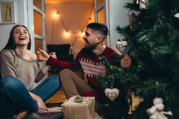 couple decorating christmas tree and preparing gifts for new year