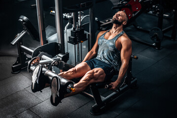 Fototapeta na wymiar Muscular man using weights machine for legs at the gym. Hard training