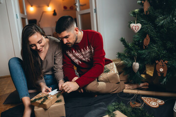 couple decorating christmas tree and preparing gifts for new year