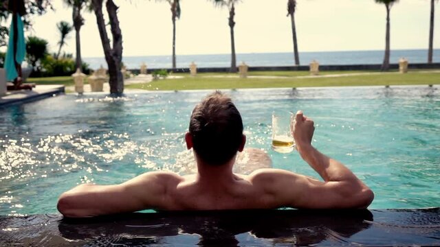 Happy man drinking beer in swimming pool, 240fps
