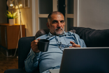 man relaxed on sofa using computer at home