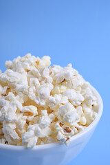 Popcorn in bowl on a blue background. Close up. Top view