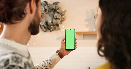 Back view of Caucasian happy married young couple man and woman at decorated house talking on video...