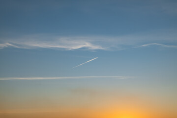 Sunset sky graduated colors with contrail, blue and orange colored sky background.