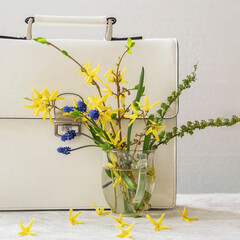 Bouquet of wild colorful flowers and white briefcase, close-up. Concept of spring stilelife, seasonal shopping