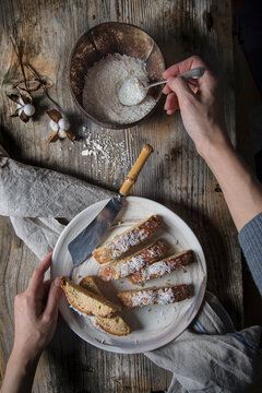 Sprinkling glazed coconut cake pieces with grated coconut