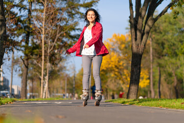 Active leisure. A sportive girl is rollerblading in an autumn park