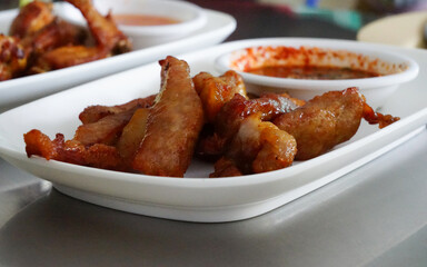 Fried sun-dried pork ready to eat in white plate with chili sauce