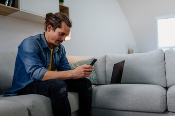 Man using a smartphone while relaxing at home