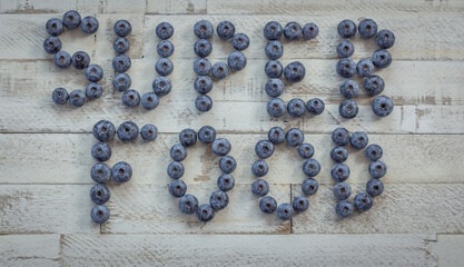 The word Superfood written with blueberries on a white vintage wooden background
