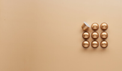 Caffeine, hot drinks and objects concept - close up of golden capsules or pods for coffee mashine on beige background. Top view with space for text. Flat lay..