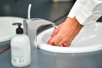 male hands being rinsed at a bathroom sink on an out of focus background