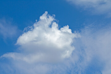 Naklejka na ściany i meble A Snow-White Cloud, Reminiscent of a Mysterious Sailboat or Bird, Floats High in The Blue Skies