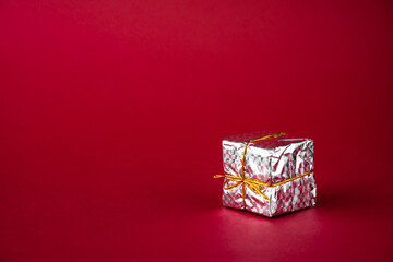 Silver holiday gift box on a red background. Copy space