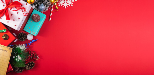 Christmas concept on a red cozy background with gifts and decorations, banner with copy space, top view