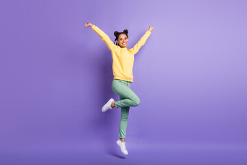 Full size photo of optimistic cute girl jump wear yellow shirt trousers sneakers isolated on lilac color background