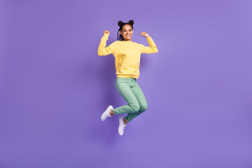 Fototapeta na wymiar Full size photo of optimistic girl jump wear yellow shirt trousers sneakers isolated on lilac color background